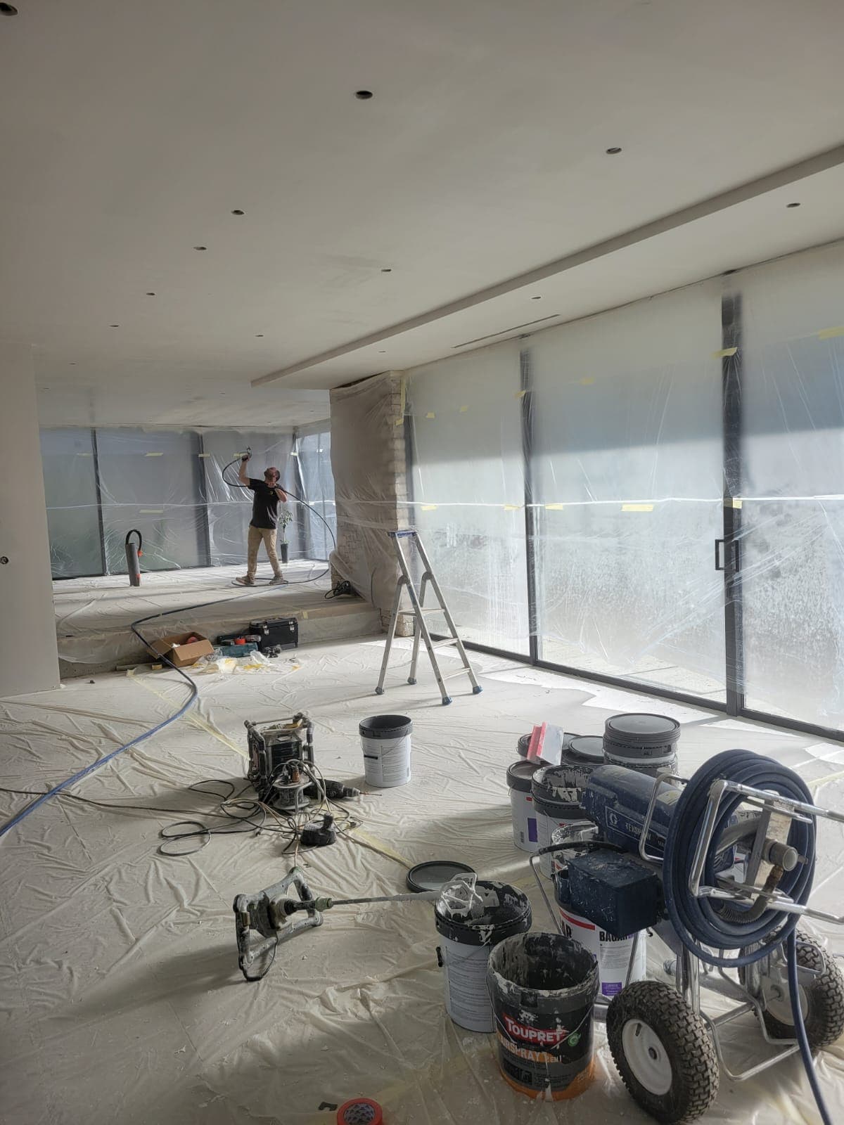 Peintre Belin Travaux appliquant la peinture au pistolet Airless sur un plafond, chantier près de Toulouse
