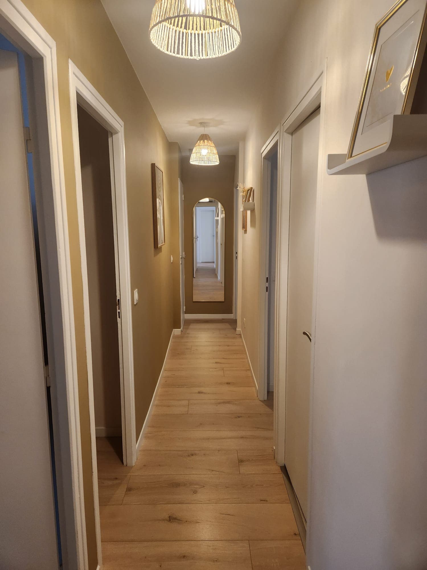 Le même couloir après travaux : mur en peinture ocre, boiseries blanches et finitions soignées par Belin Travaux