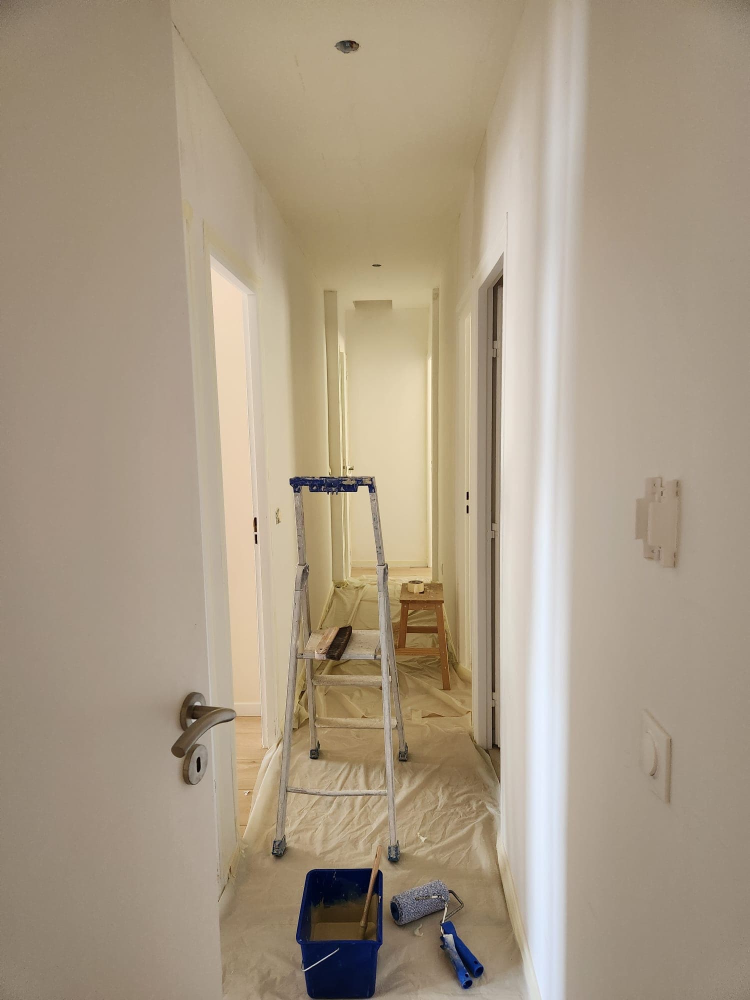 Couloir en cours de travaux, murs préparés et sol protégé, avant mise en peinture par Belin Travaux